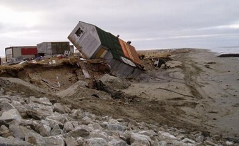 Permafrost getaut: Gekipptes Haus durch
                            Flusserosion, wenn der Fluss den aufgetauten
                            Boden wegerodiert hat, Shishmaref, Alaska,
                            "USA"